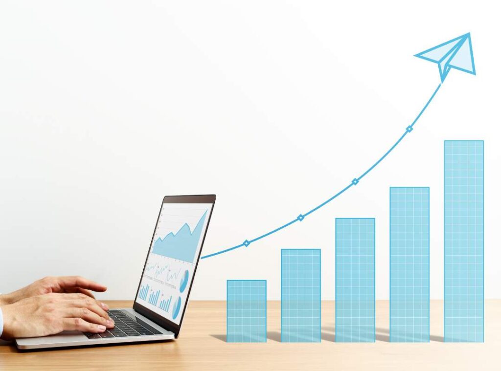 A laptop and a bar graph showing a spike that goes high.